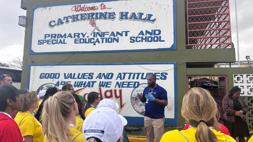 Volunteering travel advisors listen to instructions outside of Catherine Hall Primary School, where they paint and organize donations.